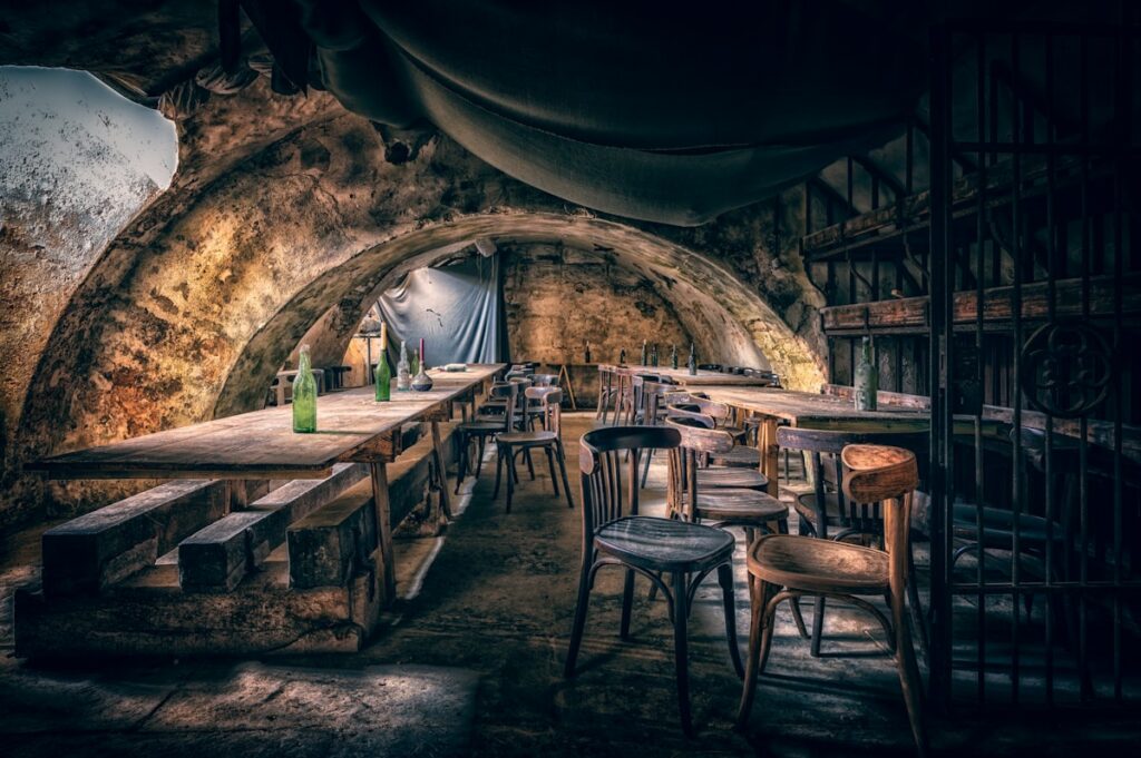 Taverne médiévale sous voûte de pierre avec tables et bancs en bois