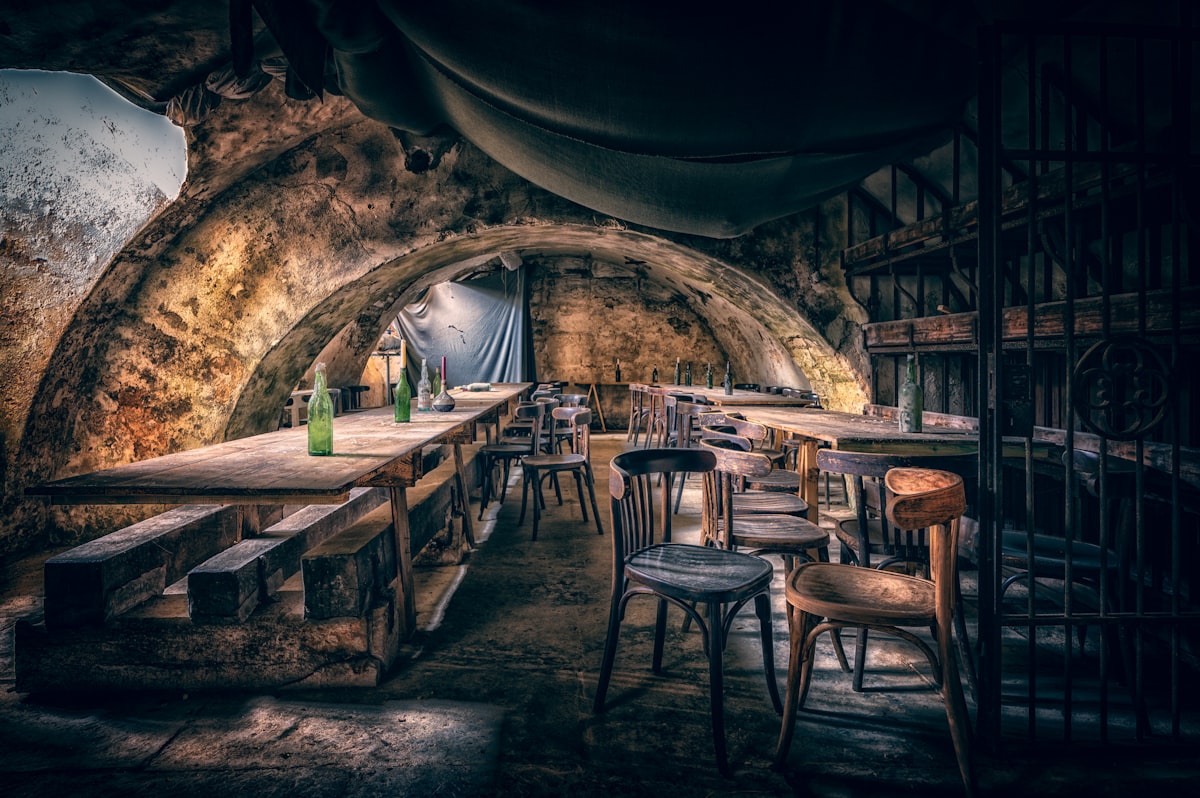 Taverne médiévale sous voûte de pierre avec tables et bancs en bois
